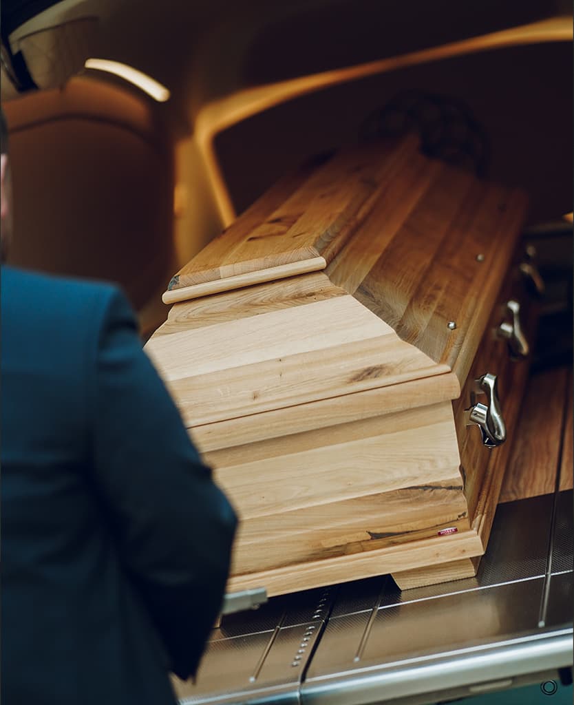 Ein Sarg der auf dem Bestattungsfahrzeug geholt wird.